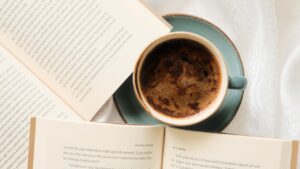 A cup of coffee and an open book on a white table